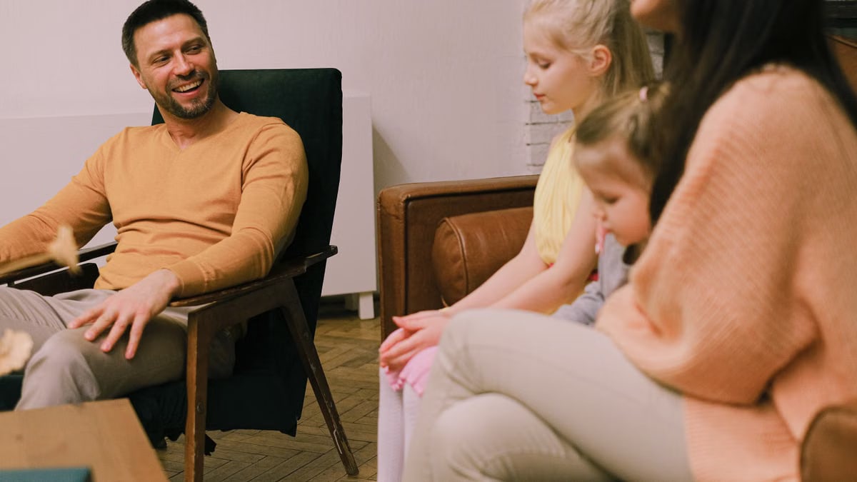 A cheerful family sitting together in the living room, sharing smiles and conversations.